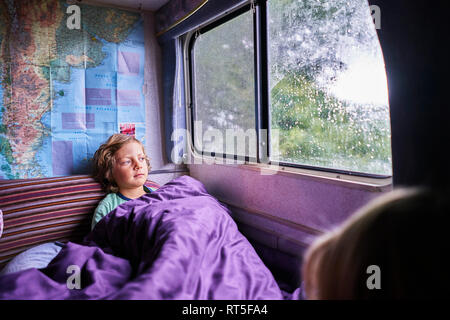 Pyjama garçon en regardant par fenêtre d'un camping- Banque D'Images