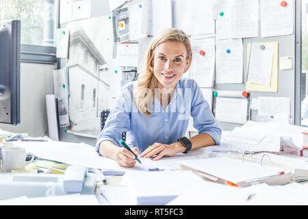 Portrait of smiling woman doing paperwork at desk in office Banque D'Images