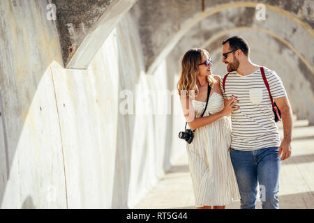 Espagne, Andalousie, Malaga, happy tourist couple marcher sous une voûte dans la ville Banque D'Images