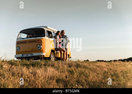 Jeune couple s'appuyant sur leur camping-car, en regardant le coucher du soleil ghe Banque D'Images