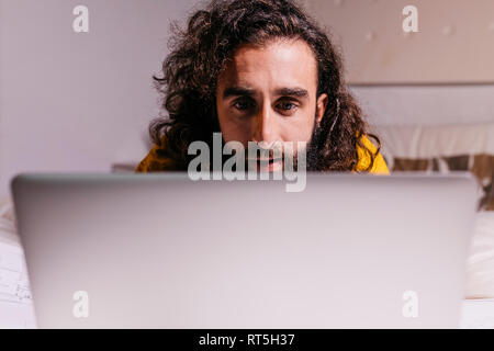 Jeune homme au lit à la maison à l'aide d'ordinateur portable Banque D'Images