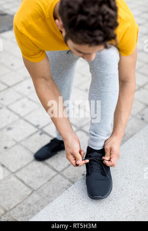 Jeune homme lors de l'entraînement, les chaussures de liage Banque D'Images