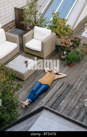 Woman relaxing on écoute la musique avec des écouteurs terrasse Banque D'Images