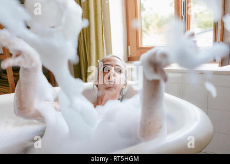 Portrait de femme dans une baignoire de jouer avec de la mousse Banque D'Images