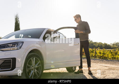 Italie, Toscane, Sienne, jeune homme sortir de voiture dans un vignoble Banque D'Images