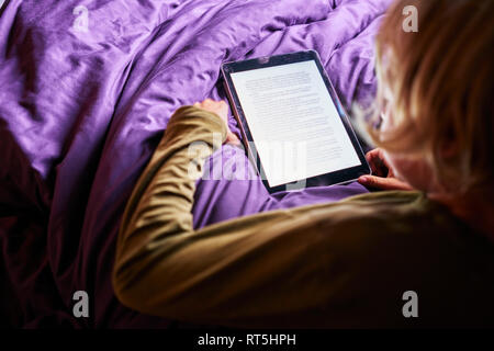 Boy reading e-livre sur tablet in bed Banque D'Images