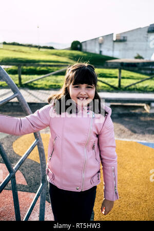 Portrait of smiling girl wearing pink blouson de cuir sur l'aire de jeux Banque D'Images