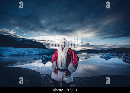 L'Islande, portrait d'un homme déguisé en Père Noël debout à un glacier Banque D'Images