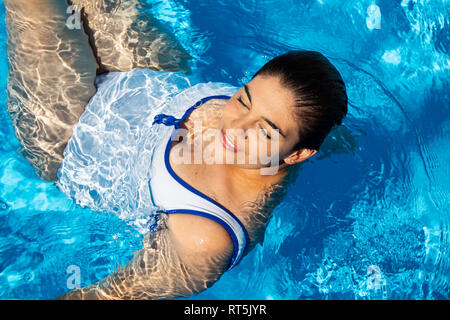 Portrait de jeune femme potelée relaxing in swimming pool Banque D'Images