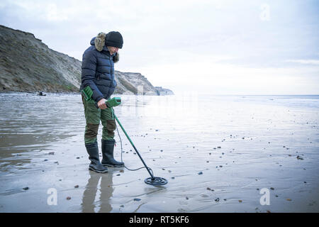 Homme avec détecteur de métal à la plage de sable Banque D'Images