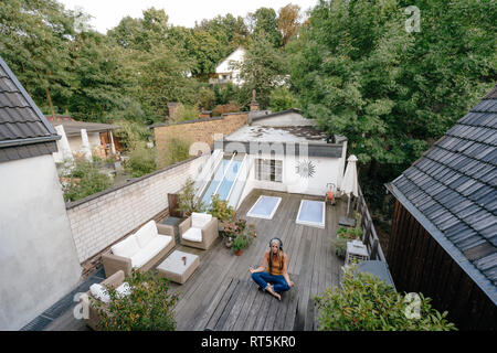 Woman sitting on terrasse faisant de l'exercice de yoga Banque D'Images