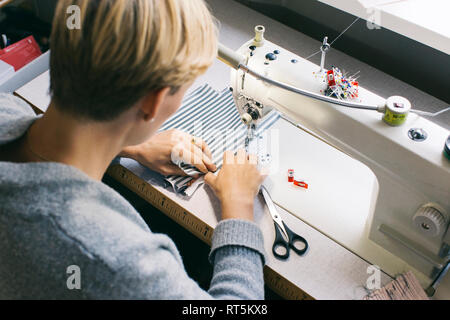 Femme à l'aide de la machine à coudre sur la table en studio Banque D'Images