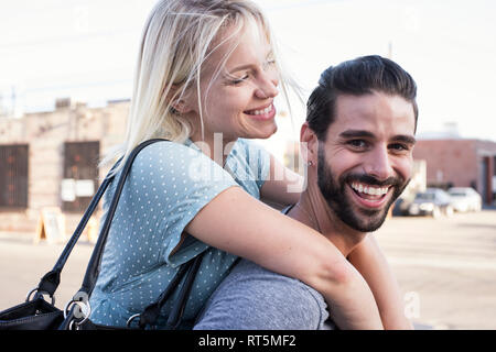 Happy young man carrying girlfriend piggyback Banque D'Images