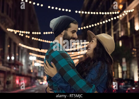 Happy young couple hugging sur la rue la nuit Banque D'Images