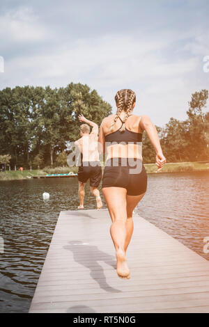 Sportifs d'exécution sur jetty, sauter dans le lac après la formation d'entraînement Banque D'Images