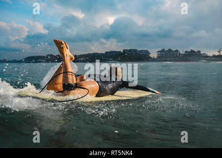 Canggu, Bali, Indonésie, femme surfer allongé sur une planche de surf Banque D'Images