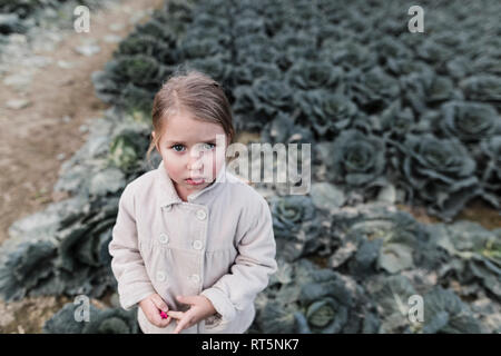 Portrait d'une jeune fille debout sur un champ de choux Banque D'Images