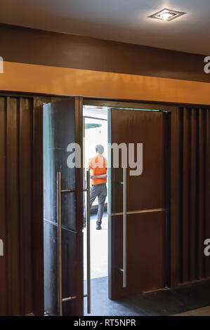 Un accompagnateur à un centre de conférence, les participants attendent d'arriver. Un cadre à l'intérieur d'un cadre-photographié par une porte partiellement ouverte. Banque D'Images