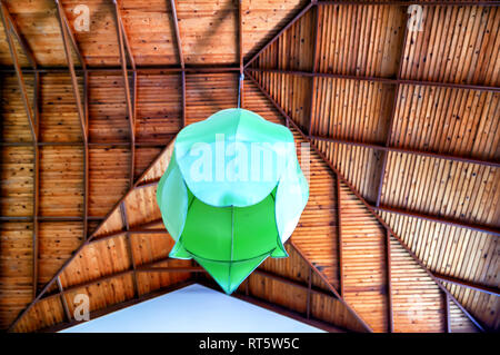 Un abat-jour vert/lustre/lampe suspendue à un très haut plafond en bois. Banque D'Images