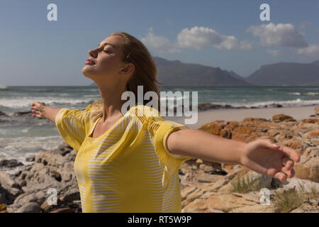 Femme debout avec les bras tendus sur la plage Banque D'Images