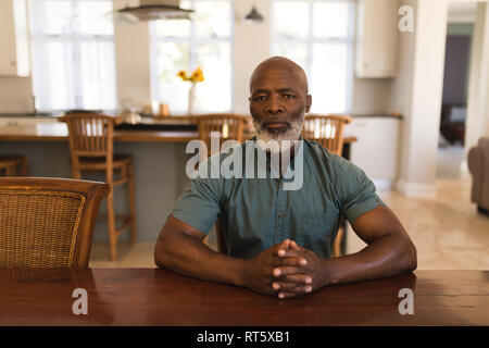 Senior man sitting at table in living room Banque D'Images