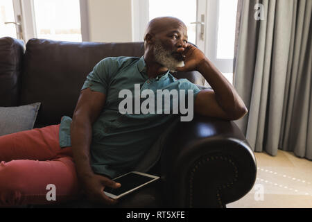 Senior man using digital tablet in living room à la maison Banque D'Images