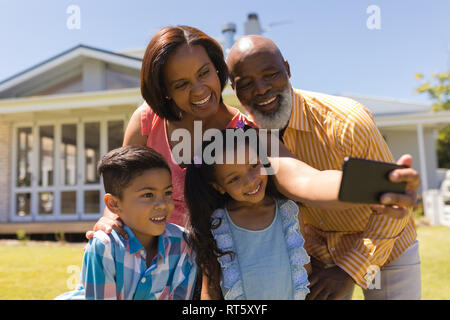 Multi-generation family en tenant avec selfies téléphone mobile à l'arrière-cour Banque D'Images