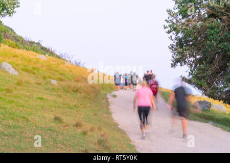 TAURANGA en Nouvelle-Zélande le 14 février 2019 ; images brouillées de grand groupe de personnes marchant sur la voie en pente du mont Maunganui au lever du soleil. Banque D'Images