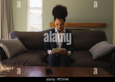 Femme d'using digital tablet in living room Banque D'Images