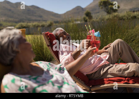 Senior couple toasting verres de cocktail dans l'arrière-cour d'accueil Banque D'Images