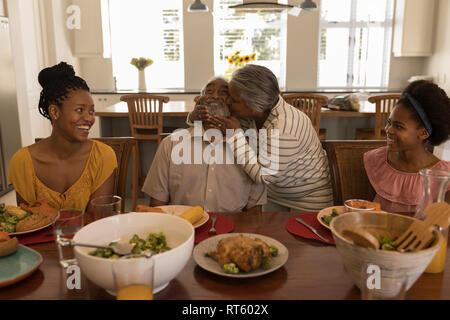 Senior woman kissing man tout en ayant des repas sur table à manger Banque D'Images