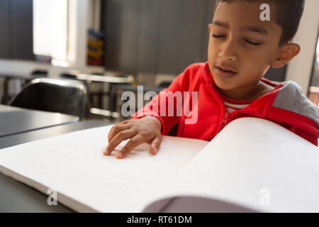 Écolier aveugle de lire un livre en braille à 24 dans une salle de classe Banque D'Images