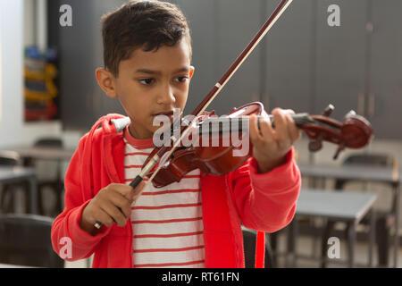 Écolier à jouer du violon en classe Banque D'Images