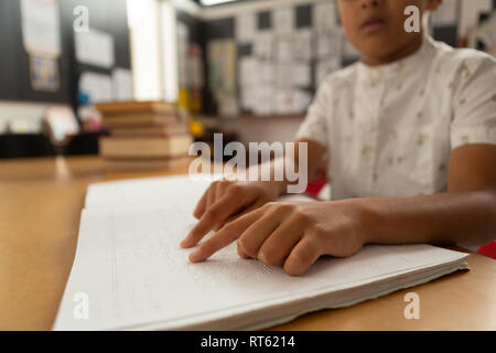 Écolier aveugle de lire un livre en braille en classe Banque D'Images