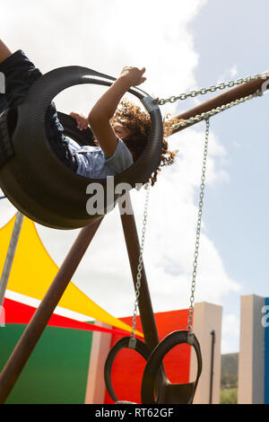 Lycéenne jouant dans un swing swing dans la cour de l'école Banque D'Images