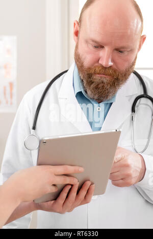 Doctors discussing report sur un patient à tablet computer in hospital Banque D'Images