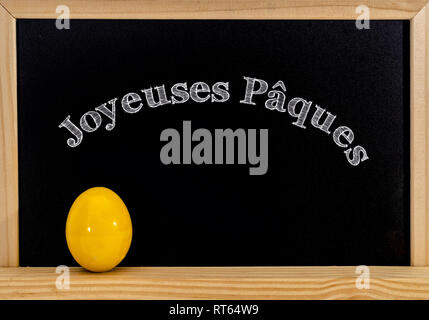 Châssis de Pâques avec des oeufs peints et tableau. Joyeuses Pâques dans la craie blanche. Joyeuses Pâques en français : joyeuses paques Banque D'Images