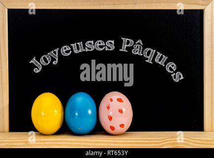 Châssis de Pâques avec des oeufs peints et tableau. Joyeuses Pâques dans la craie blanche. Joyeuses Pâques en français : joyeuses paques Banque D'Images