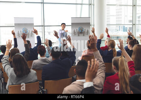 Les gens d'affaires soulevant les mains dans un séminaire d'entreprise Banque D'Images