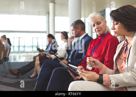 Businesswomen discussing sur tablette numérique au cours de séminaire d'entreprise Banque D'Images
