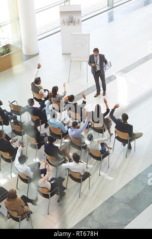 Groupe d'entreprises diversifié de personnes lèvent la main pour poser des questions à man. Banque D'Images