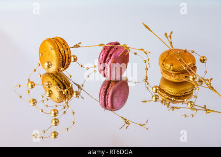 Délicieux macarons colorés isolé fait maison sur un miroir et un fond coloré décoration contemporaine et réflexions Banque D'Images