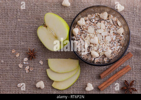 Alimentation saine. Muesli dans un bol sur un fond clair avec une pomme verte. Petit-déjeuner bouillie sur fond lin. Banque D'Images