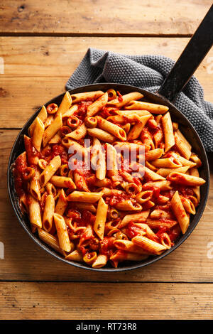 Pâtes penne avec appétissant savoureuse sauce tomate et olives servi sur la casserole. Fond de bois. Libre. Banque D'Images