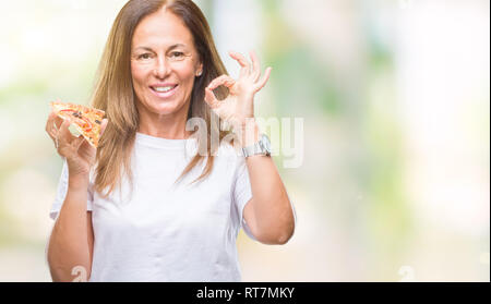 L'âge moyen hispanic woman eating pizza slice sur fond isolé ok faire signer avec les doigts, symbole excellent Banque D'Images