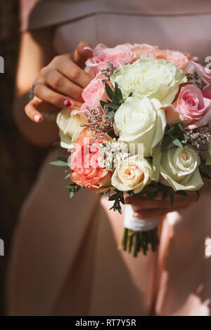 Beau mariage bouquet de roses crème dans les mains de la mariée. Banque D'Images