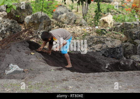 BALI, INDONÉSIE - 10 Nov 2018 : Un enfant indonésien creuser un trou dans un sable Banque D'Images