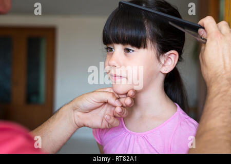 Coupe les cheveux de la fille du père à la maison Banque D'Images