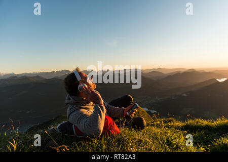 Randonneur couché dans l'herbe, faire une pause et d'écoute de la musique avec des écouteurs Banque D'Images