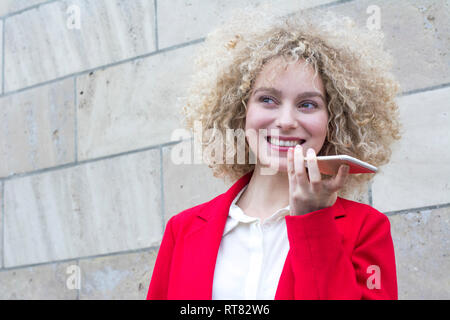 Portrait of smiling blonde woman with anglaises à parler au téléphone Banque D'Images